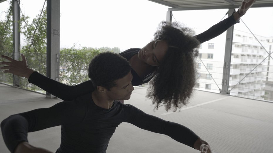 eine Frau und ein Mann tanzen Ballett auf dem Dach eines Gebäudes