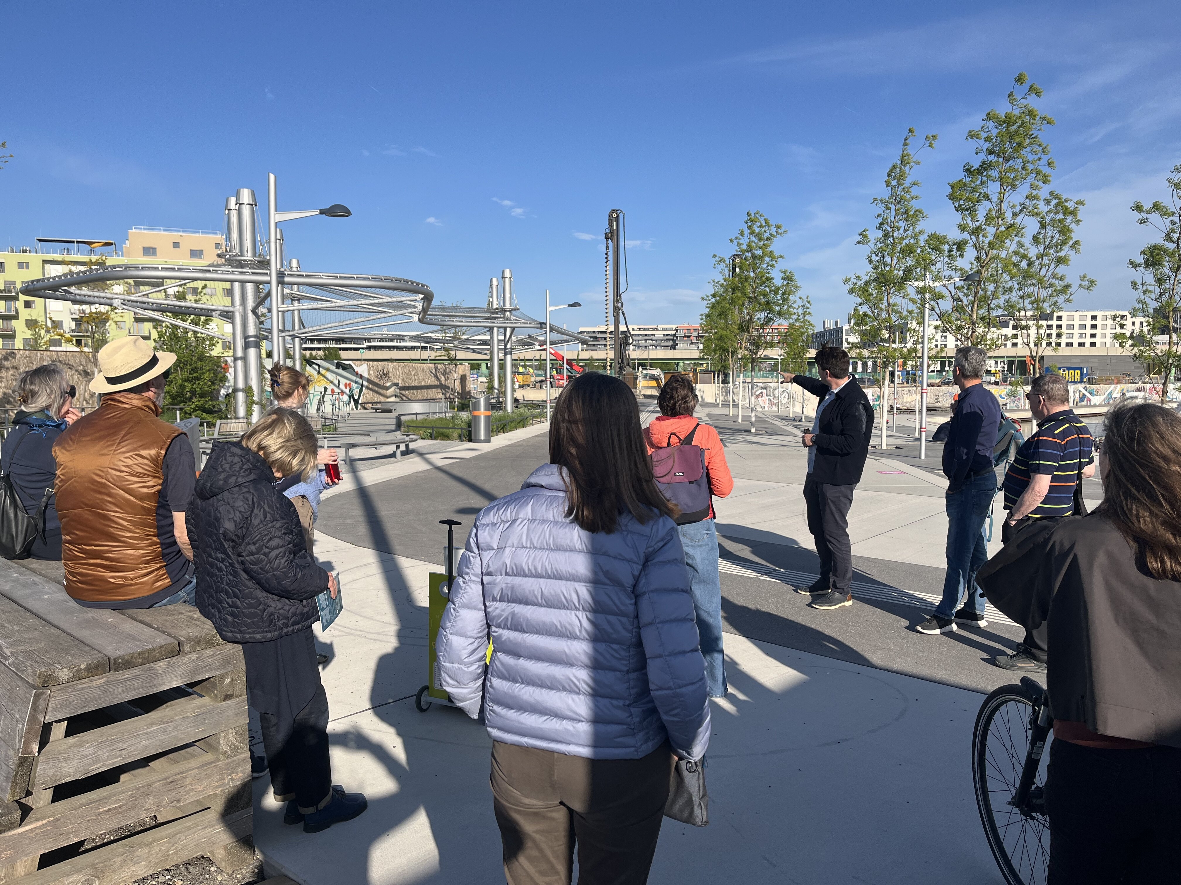 Gruppe hört dem Guide bei einer Tour durch die Seestadt zu, Tourguide zeigt auf etwas im Hintergrund 