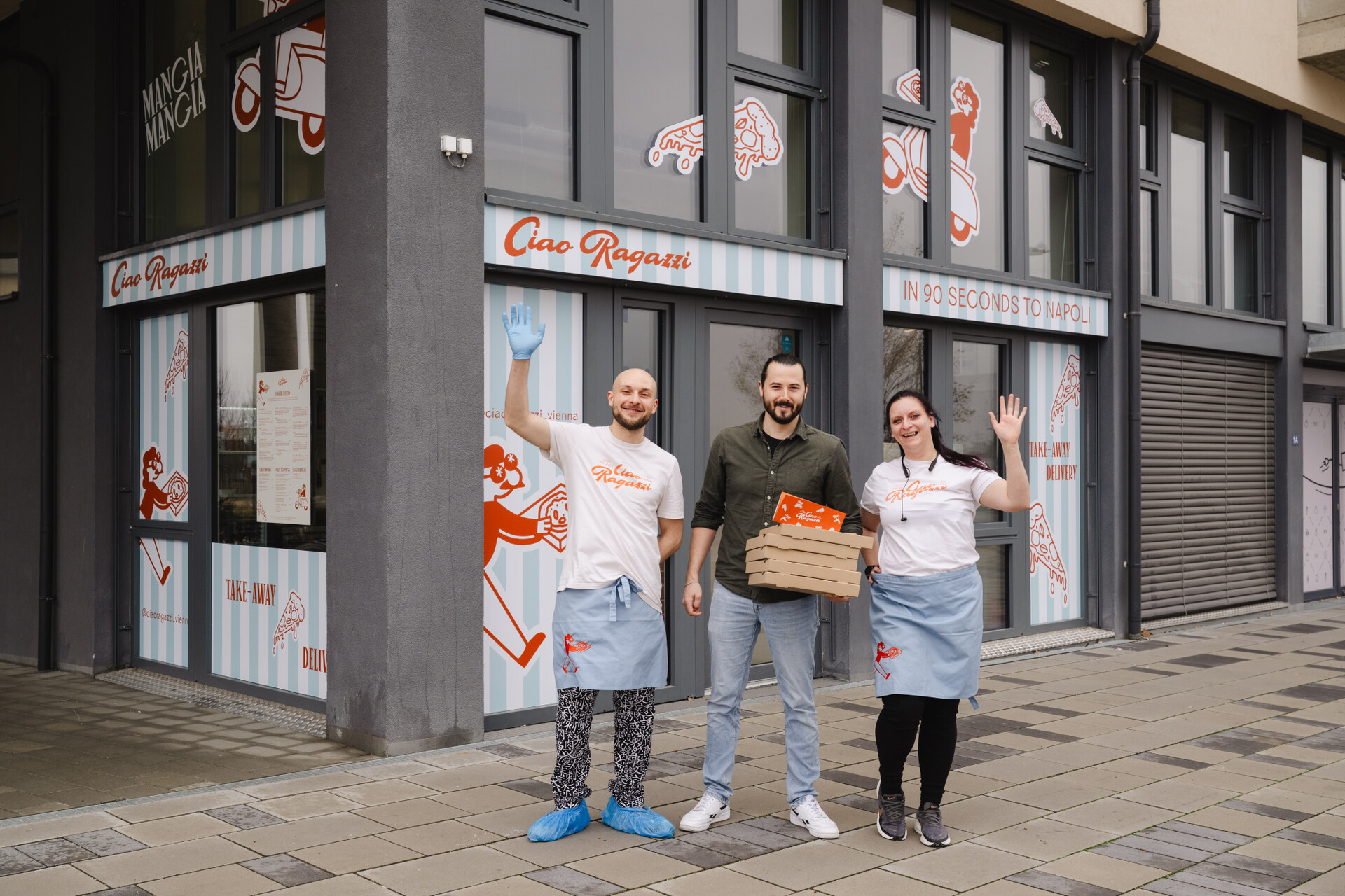 Zwei Mitarbeiter und der Inhaber von Ciao Ragazzi stehen als Gruppe vor dem Lokal und winken 