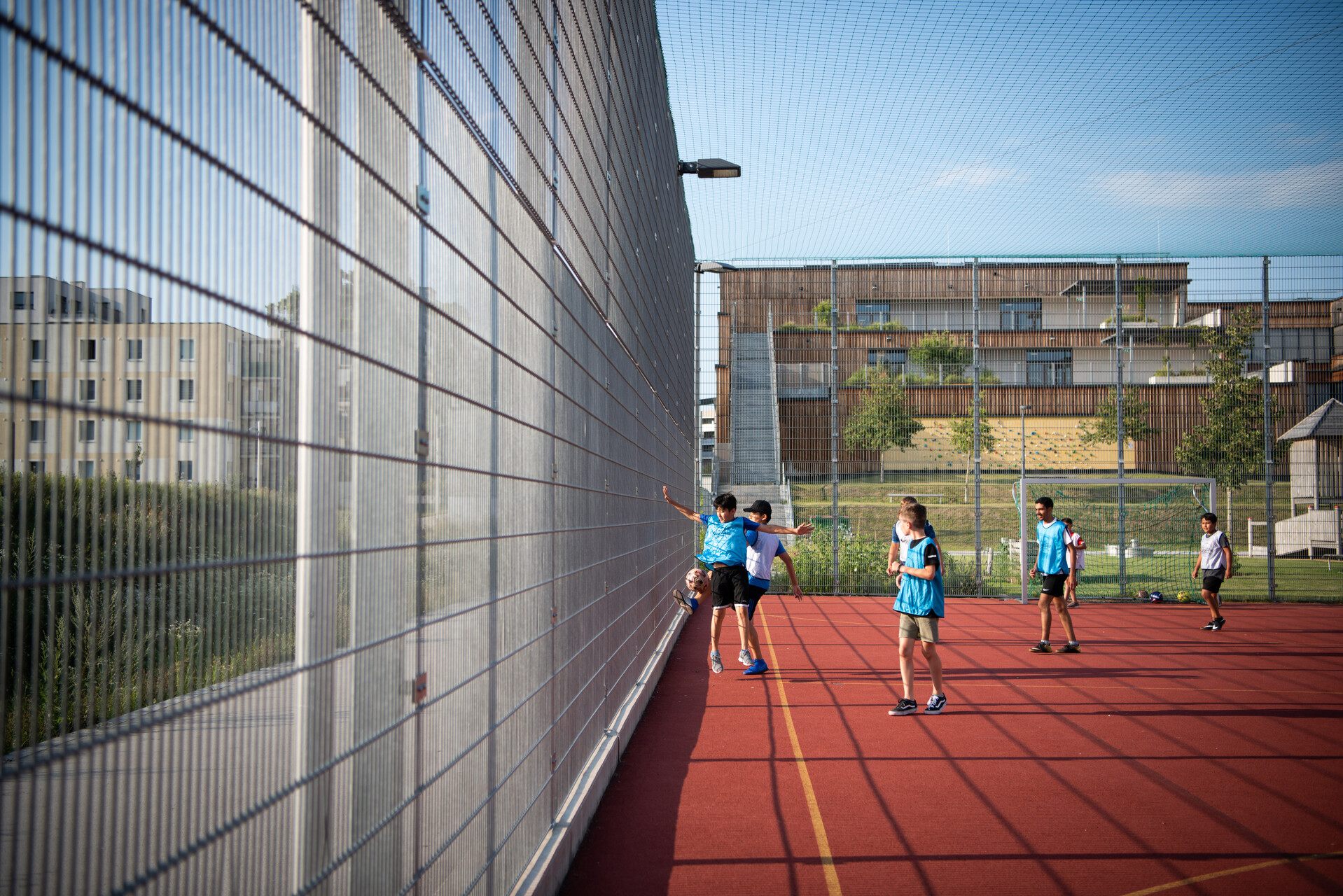 Kinder spielen in einem roten Käfig Fußball