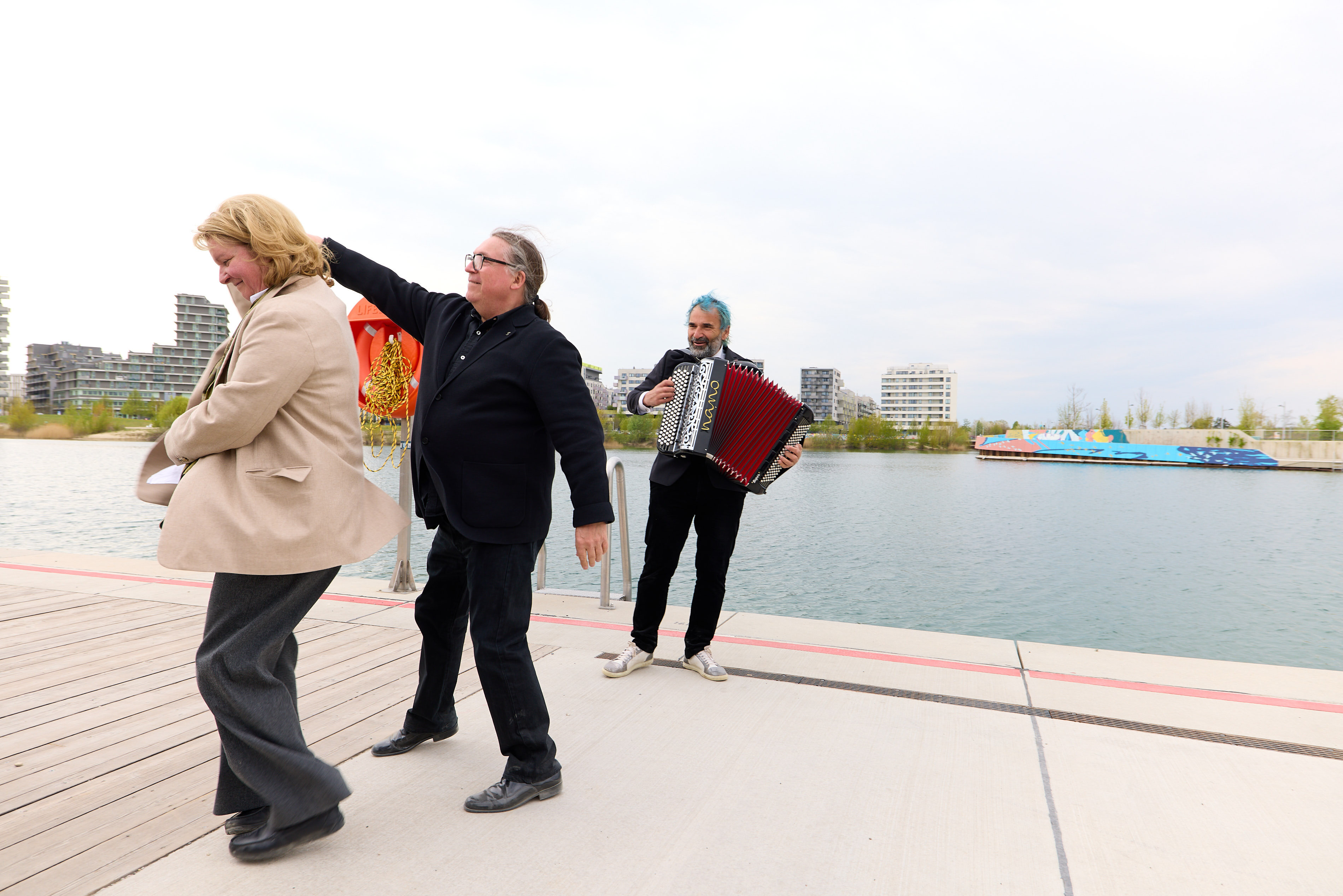 Zwei Personen tanzen am Seeufer, während ein Musiker Akkordeon spielt bei LILY am See Veranstaltung.