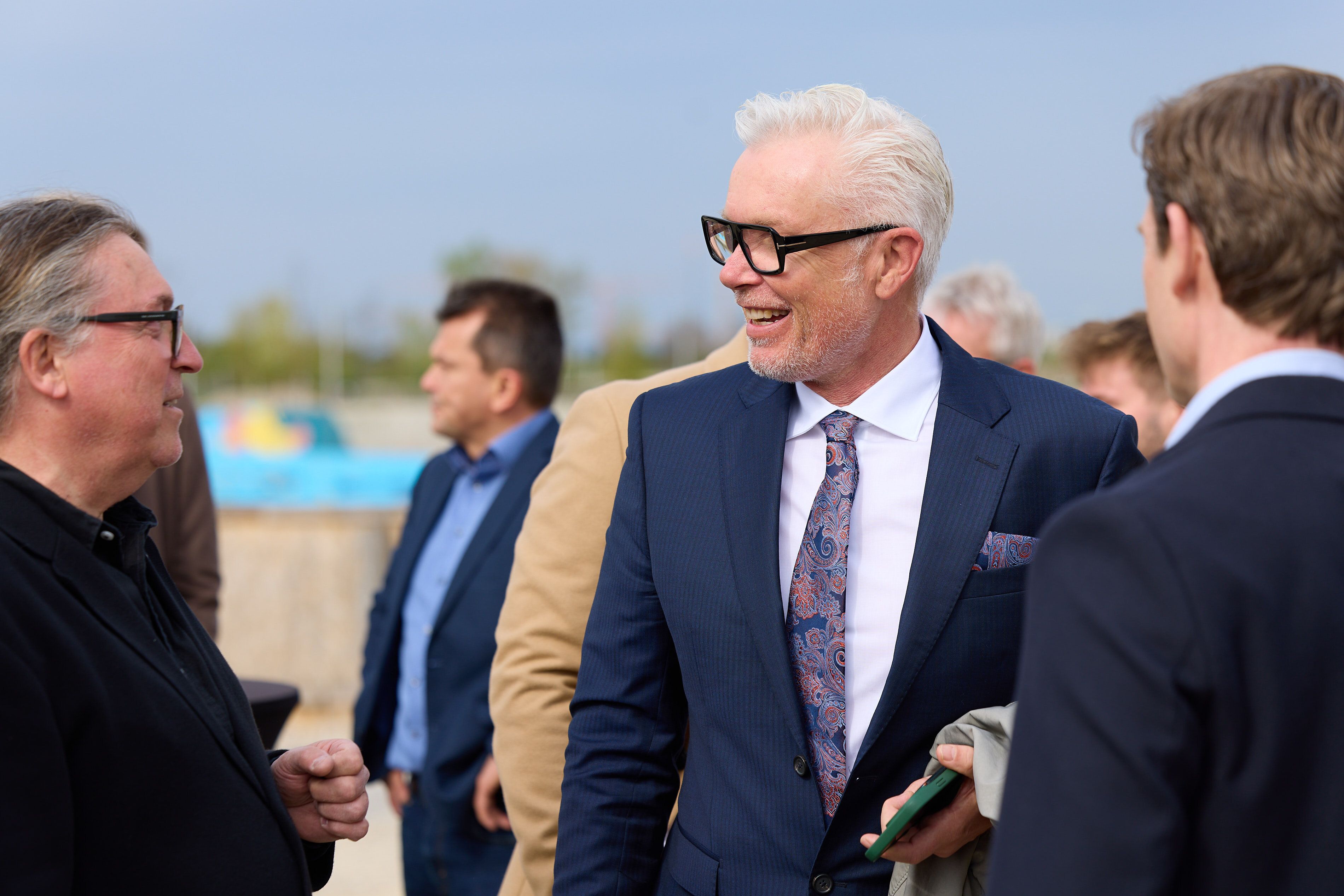 Teilnehmer unterhalten sich bei Veranstaltung LILY am See, Mann im Anzug lacht im Gespräch.