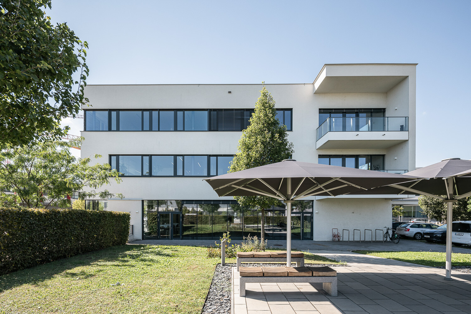 Bürogebäudes mit weißer Fassade, großen Fenstern und Garten.