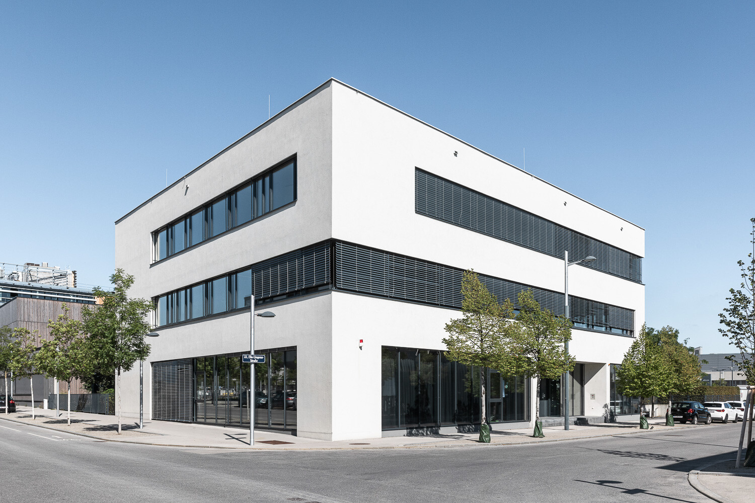 Modernen, kubischen Bürogebäudes mit weißer Fassade und großen, rechteckigen Fenstern.