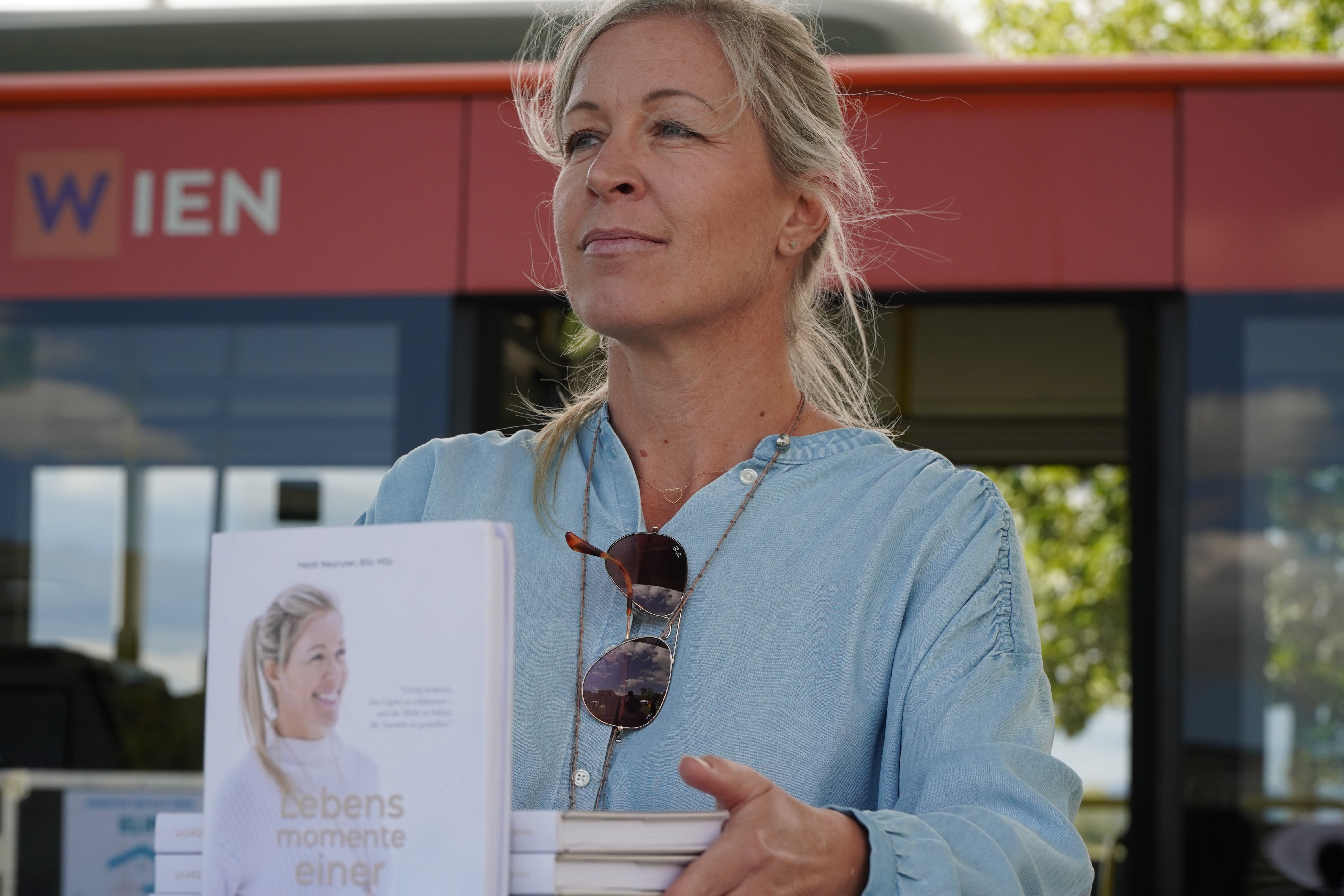 Snowboard Weltmeisterin Heidi Neururer präsentiert ihr neues Buch beim Sportfest. Person stehend mit Büchern