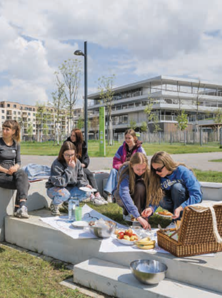 Sechs junge Frauen, die im Park sitzen und ein Picknick machen.