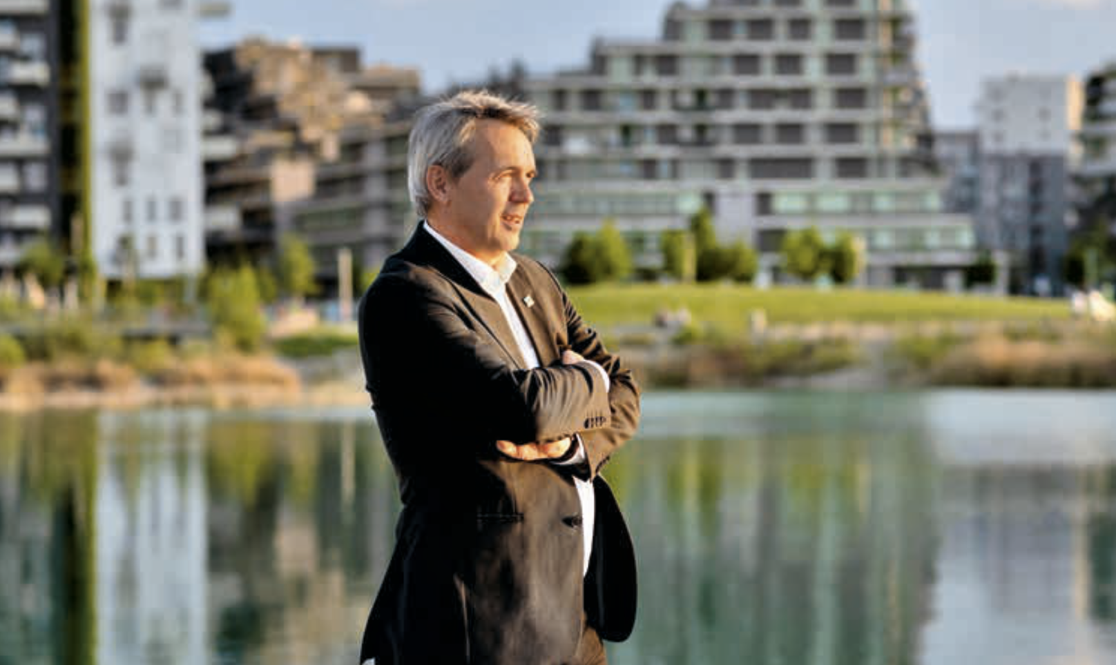 Mann mit Anzug, der vor einem See steht.