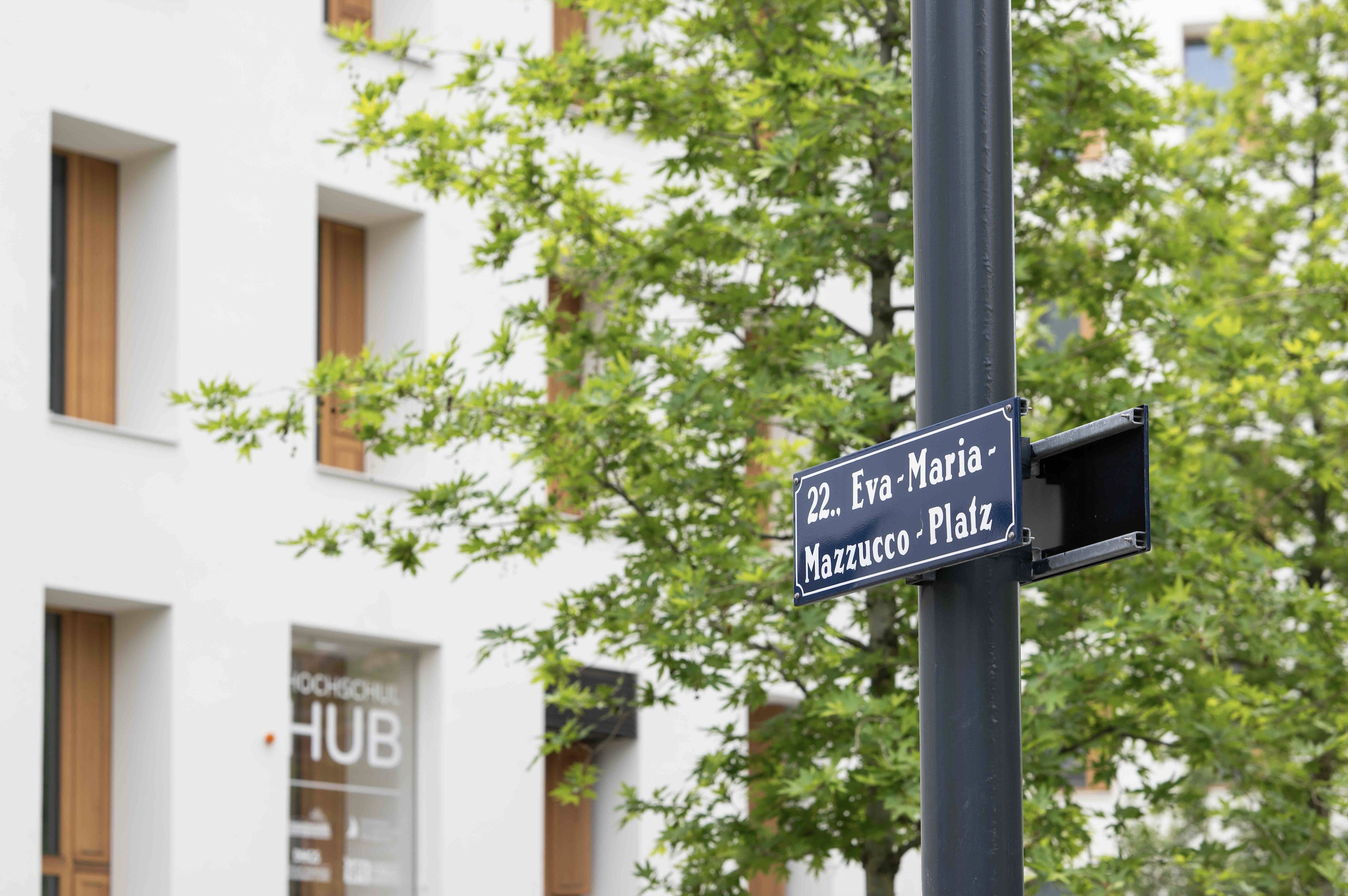 Dunkelblaues Straßenschild in urbaner Umgebung. 