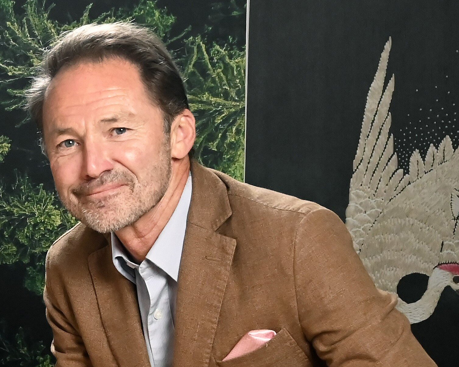 Mann mit hellbraunem Blazer und hellem Hemd.
