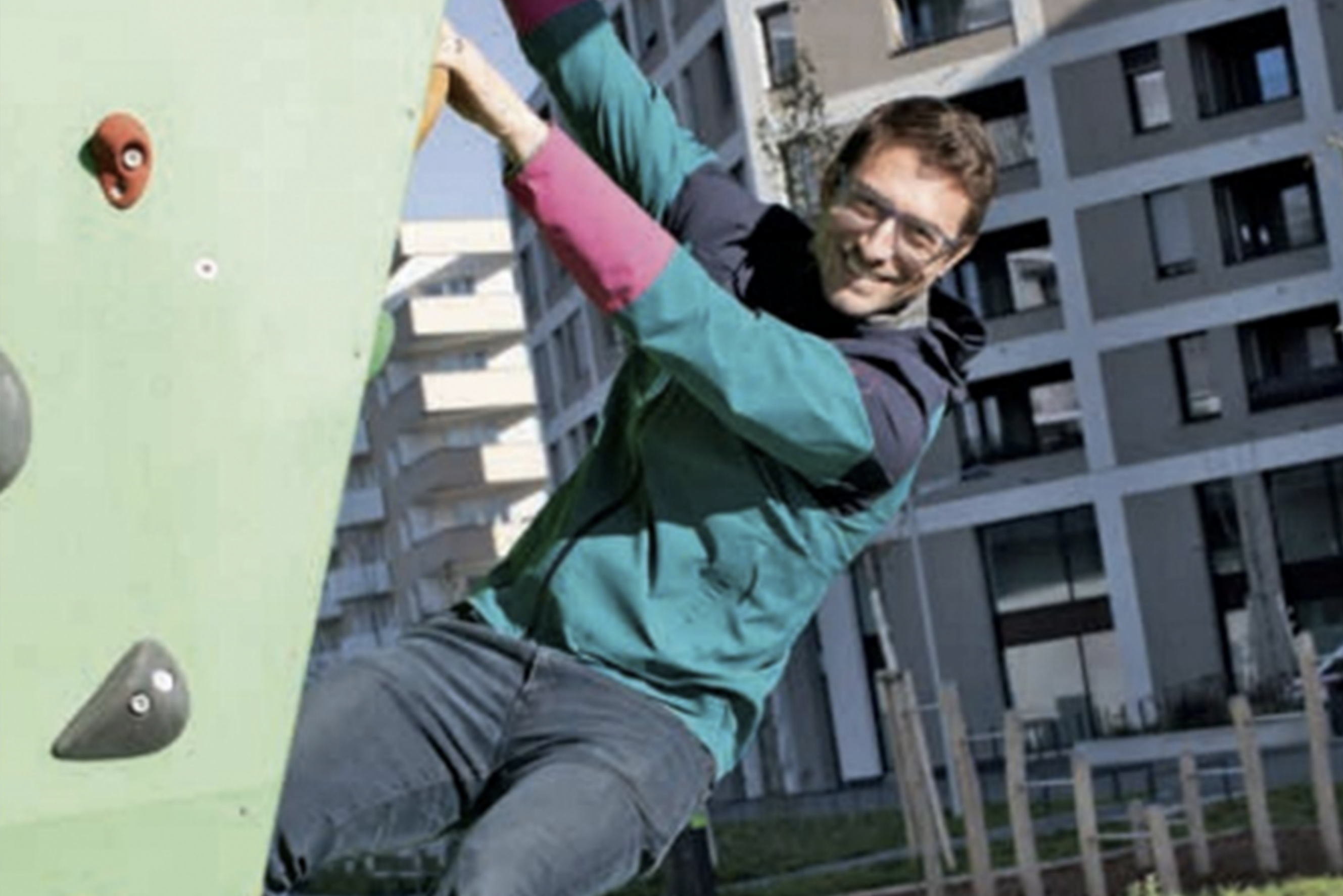 Mann mit Brille auf einer Kletterwand.