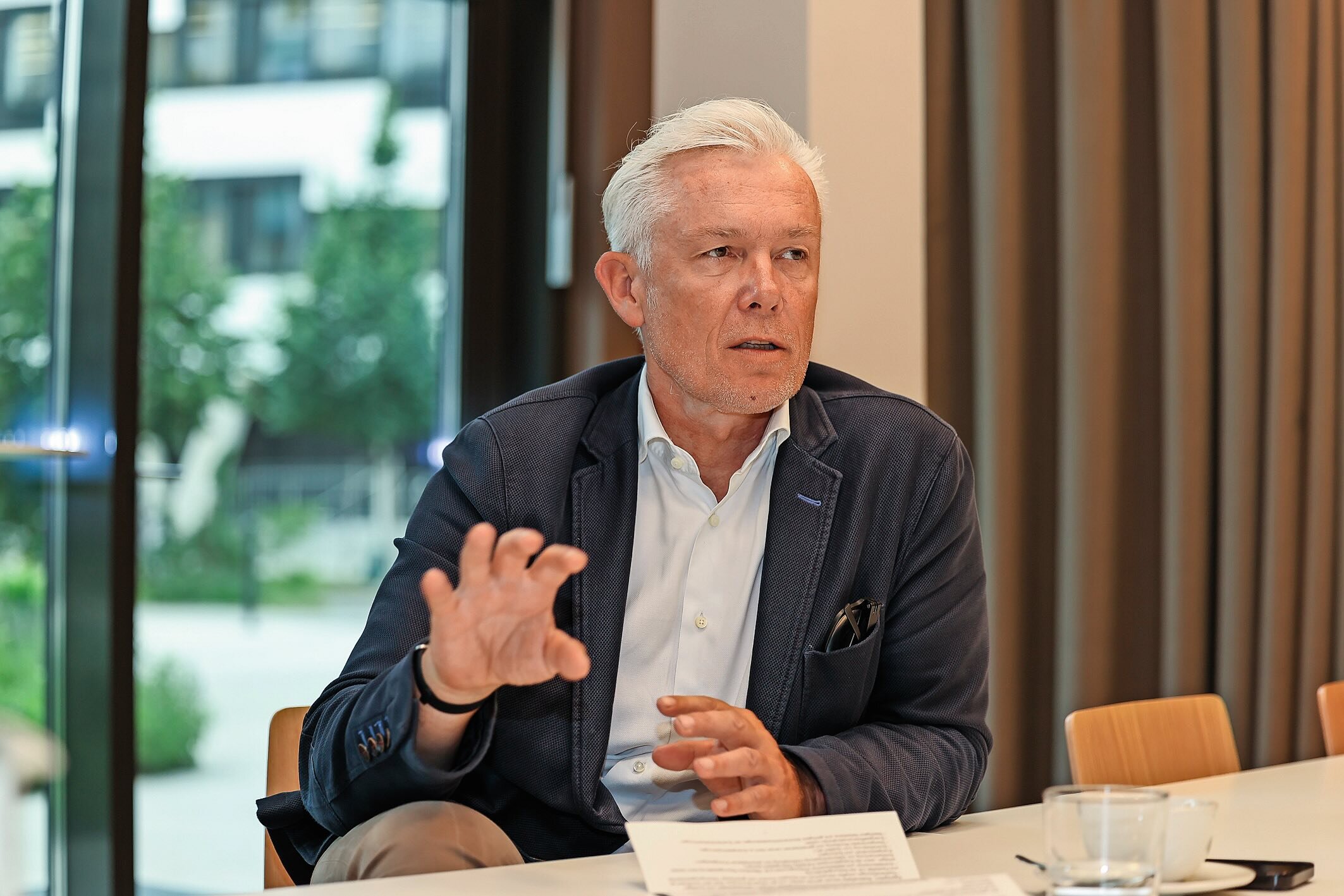 Mann mit schwarzer Lederjacke sitzt beim Tisch.