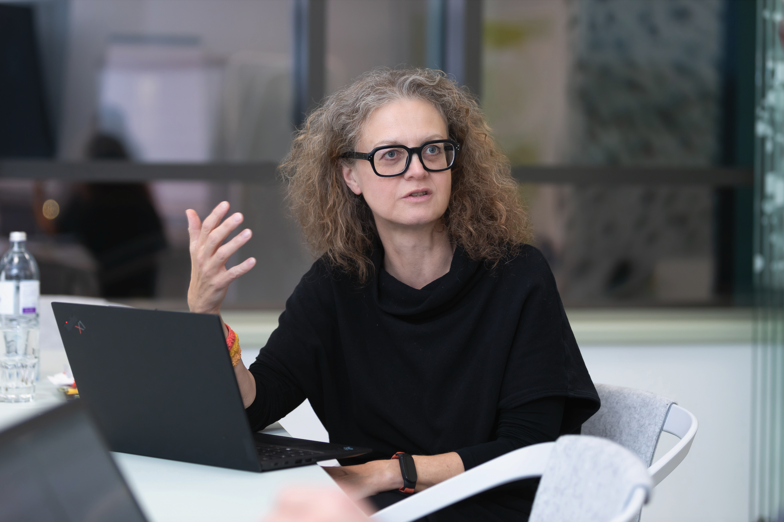 Frau mit schwarzem Oberteil vor dem Laptop.