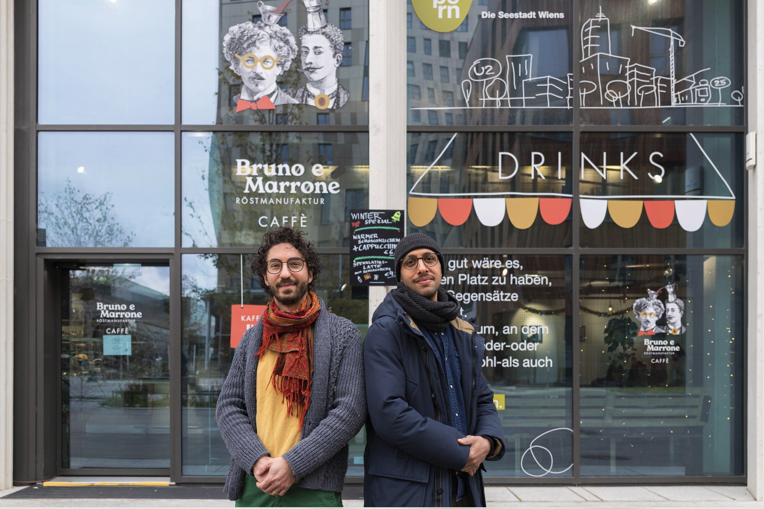 Zwei Herren stehen vor einem Cafe. 