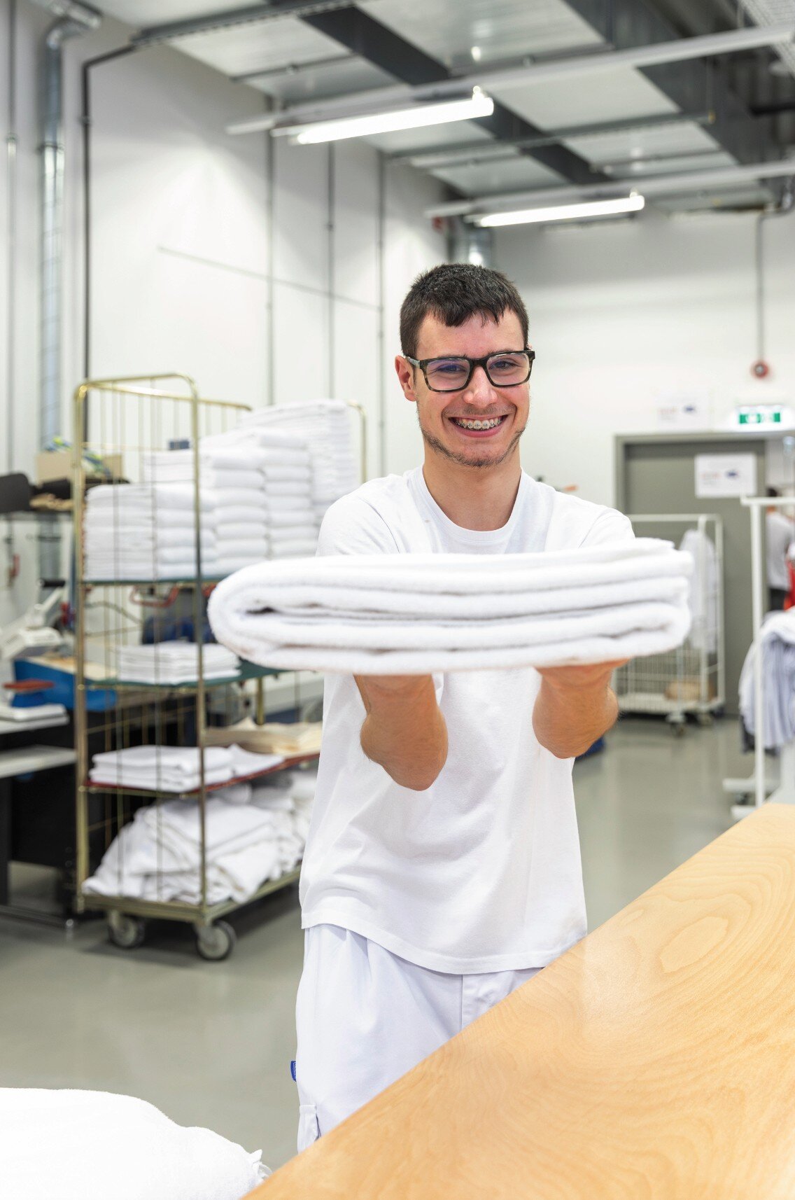 Mann in weißer Arbeitsbekleidung hält Handtücher in der Hand. 