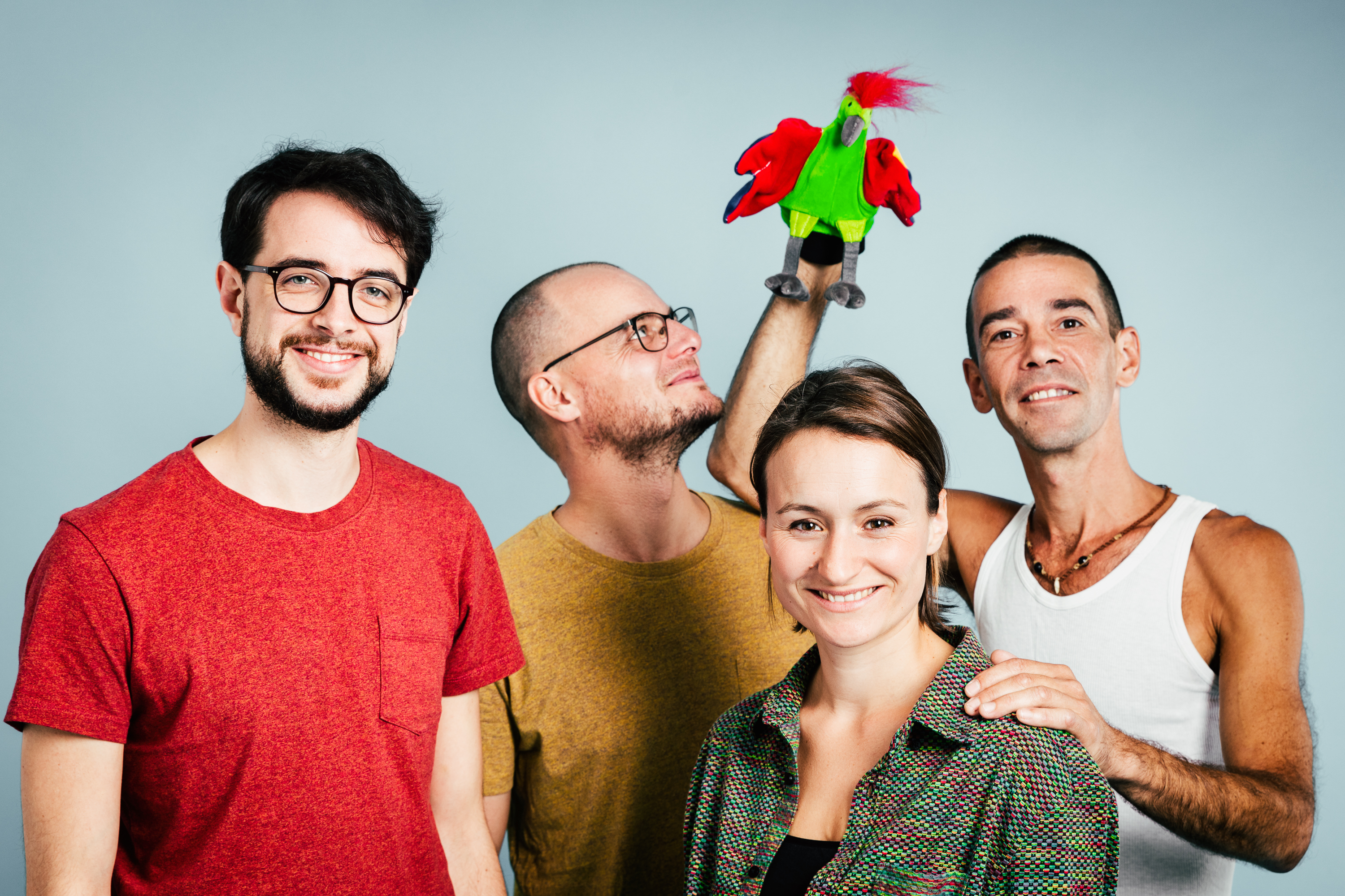 Ein Gruppenbild mit 3 Männern und einer Frau, ein Mann hält eine Handpuppe in Form eines grün-roten Papageis. 
