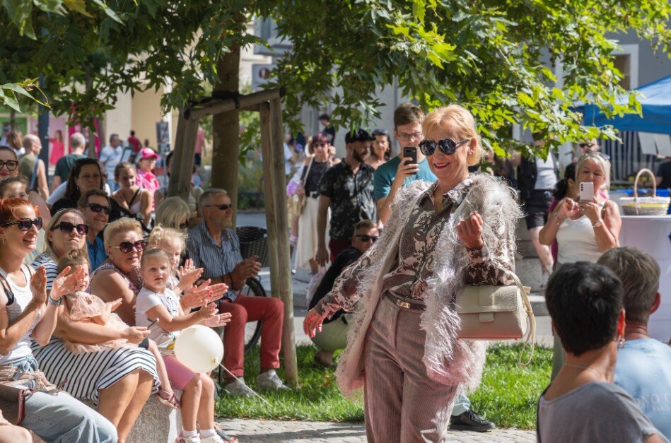 Sitzendes und stehendes Publikum, das in die Hände klatscht, in einem Park bei Sonnenschein. 