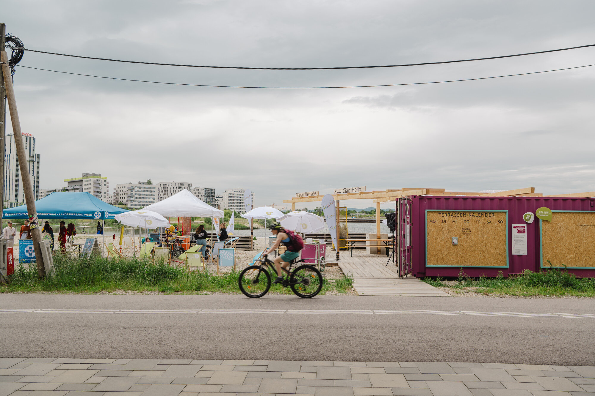 Foto einer Radfahrerin vor der Nachbarschafts-Terrasse des Stadtteilmanagements