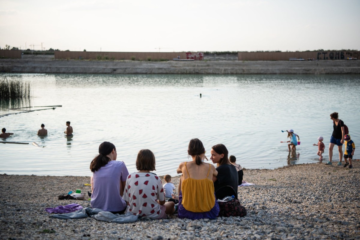 Kinder sitzen am Seeufer mit Blick auf den See