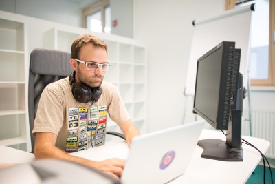 männlich gelesener Mensch an der Tastatur vor einem Computerbildschirm