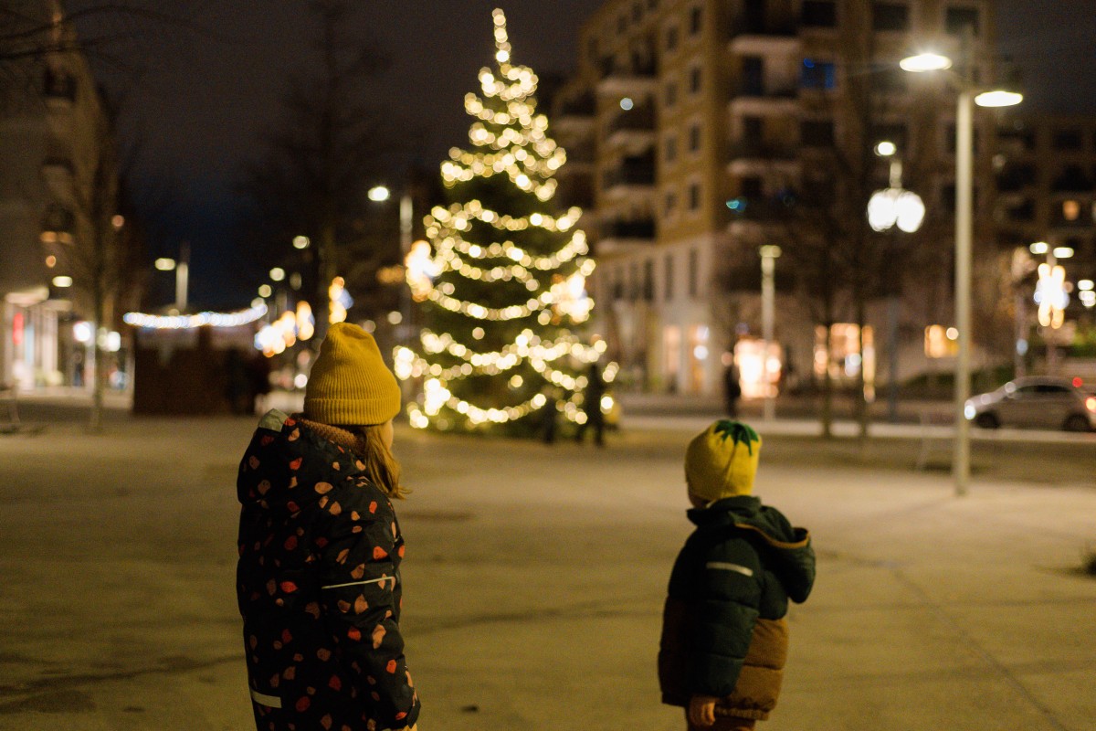 Kinder stehen vor einem Weihnachtsbaum im Freien