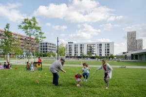 Erwachsene spielen mit Kind auf grüner Wiese Springschnur