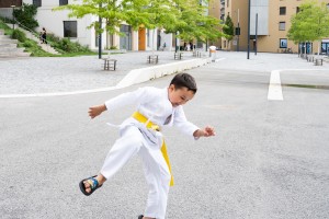 Junge in weißem Kampfanzug und gelben Gürtel springt