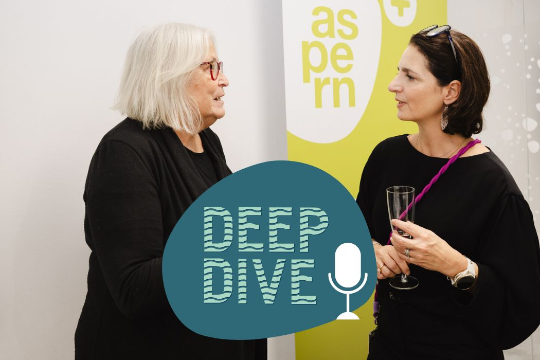 Zwei Frauen vor einem aspern Rollup sprechen miteinander.